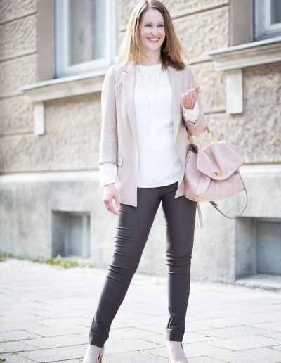 Frau im Business Outfit mit Nudefarbenem Blazer, brauner Hose, weißer Bluse, nudefarbener Tasche und nudefarbenen Pumps